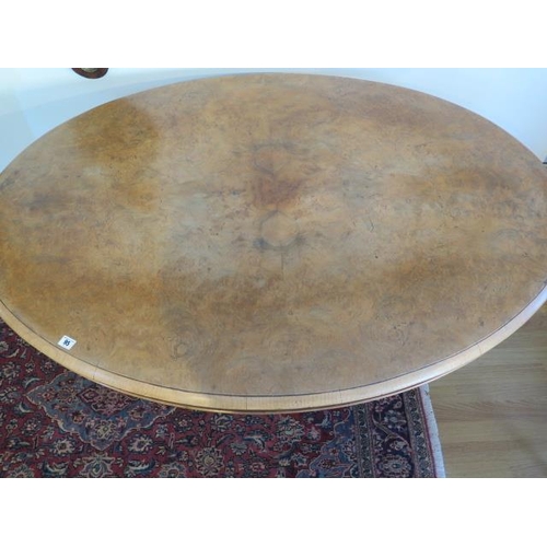 95 - A Victorian burr walnut tilt top oval breakfast / dining table, on turned and carved column and quat... 