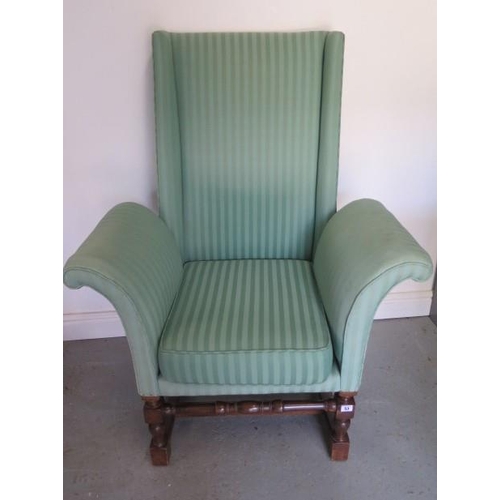 53 - A mahogany upholstered mahogany wingback chair with exaggerated scroll arms, 116cm tall x 87cm wide,... 
