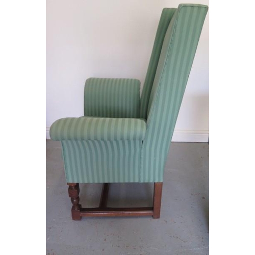 53 - A mahogany upholstered mahogany wingback chair with exaggerated scroll arms, 116cm tall x 87cm wide,... 