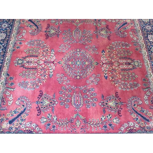 201 - A hand knotted woollen rug with a red field, some slight wear but no holes, 215cm x 203cm