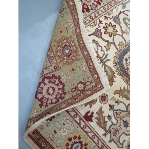 203 - A hand knotted woollen rug with a cream field, 323cm x 247cm