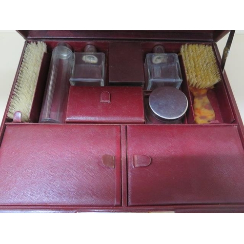 317 - A vintage red leather fitted travel case with bottles, brushes and other fittings, 14cm x 37cm x 30c... 