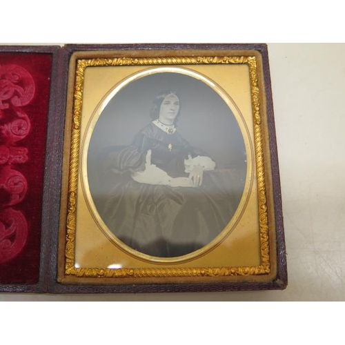 321 - A hand tinted ambrotype portrait of a lady in a decorative velvet lined clasped case with gold frame... 