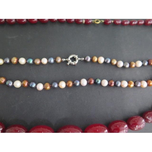 463 - A string of cherry amber type beads, largest 3cm x 2cm, 82cm long, also with a coloured pearl neckla... 