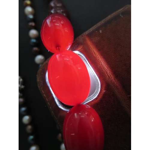 463 - A string of cherry amber type beads, largest 3cm x 2cm, 82cm long, also with a coloured pearl neckla... 