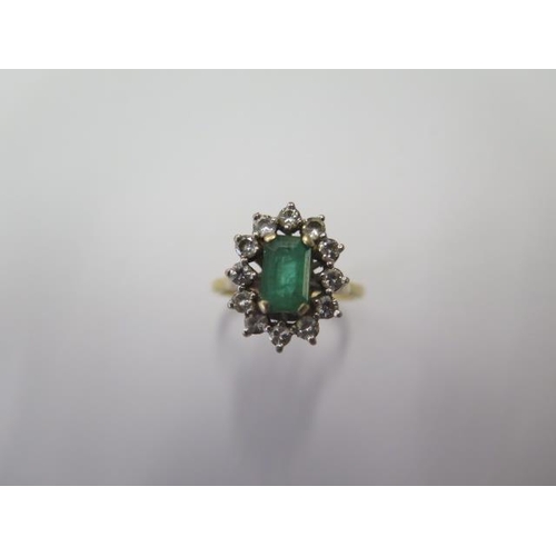 503 - A hallmarked 18ct yellow gold emerald and diamond cluster ring, the emerald approx 8mm x 5mm x 3mm, ... 