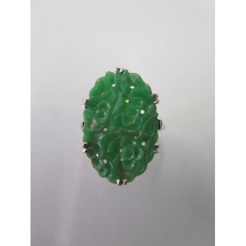 An 18ct platinum carved jade ring, head approx 22mm x 15mm, size N, jade has been broken and glued, total weight approx 4.2 grams
