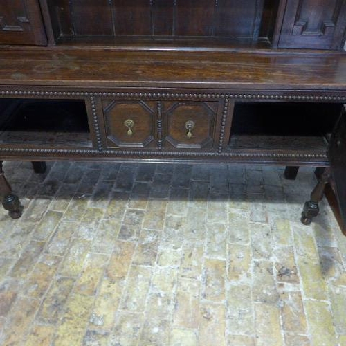 37 - An oak 18th century style dresser with a two cupboard open rack top above a single drawer two door b... 