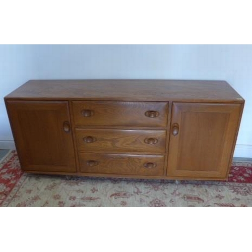 91 - An Ercol elm sideboard with three drawers and two cupboard doors on casters - Height 69cm x 155cm x ... 