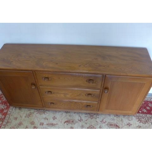 91 - An Ercol elm sideboard with three drawers and two cupboard doors on casters - Height 69cm x 155cm x ... 