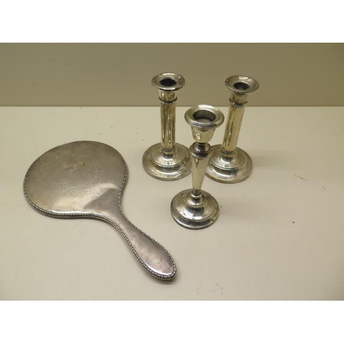 507 - Three weighted silver candlesticks - Tallest 14cm - and a silver back mirror