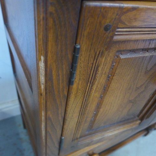 37 - A pair of Ercol autumn gold elm cabinets with two doors above a drawer on turned supports united by ... 