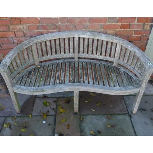 38 - A weathered teak banana shaped garden bench - Height 84cm x 157cm