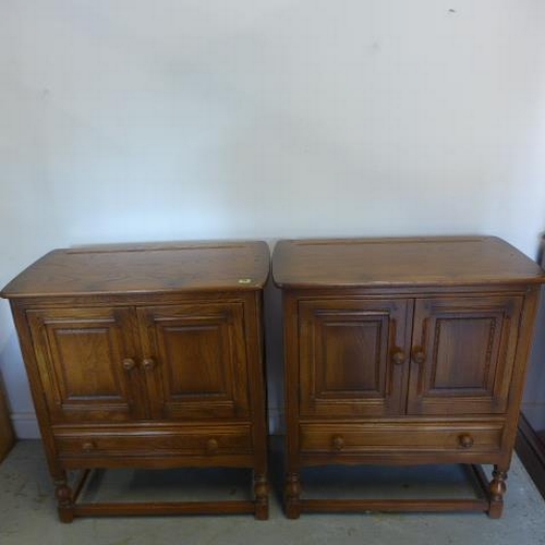 31 - A pair of Ercol autumn gold elm cabinets with two doors above a drawer on turned supports united by ... 