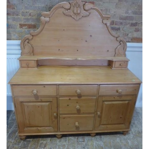 24 - A stripped pine Victorian style dresser with a carved back above five drawers and two cupboard doors... 
