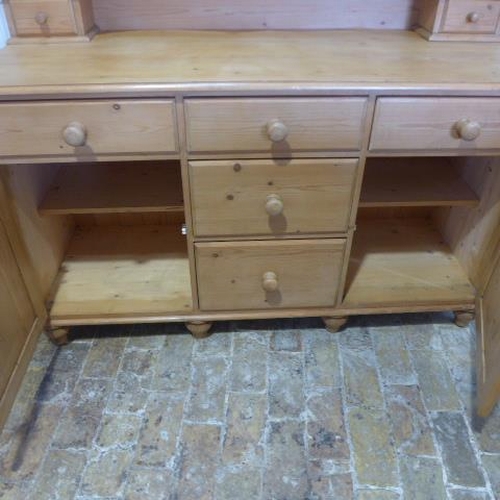 24 - A stripped pine Victorian style dresser with a carved back above five drawers and two cupboard doors... 
