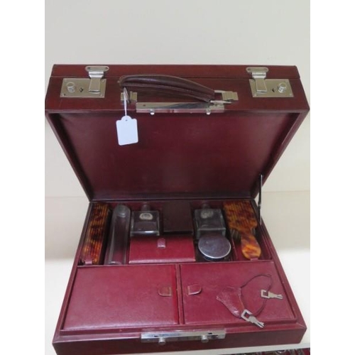 211 - A vintage maroon leather travel case with a fitted interior of bottles, brushes, manicure, mirror an... 