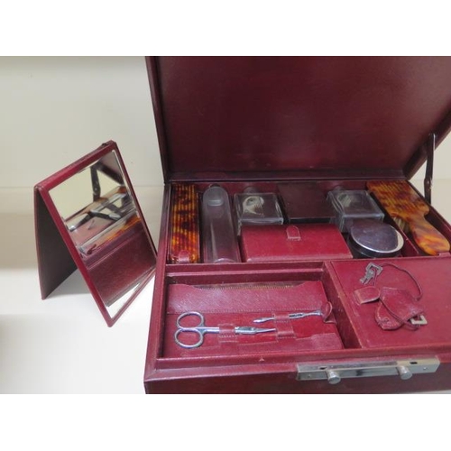 211 - A vintage maroon leather travel case with a fitted interior of bottles, brushes, manicure, mirror an... 