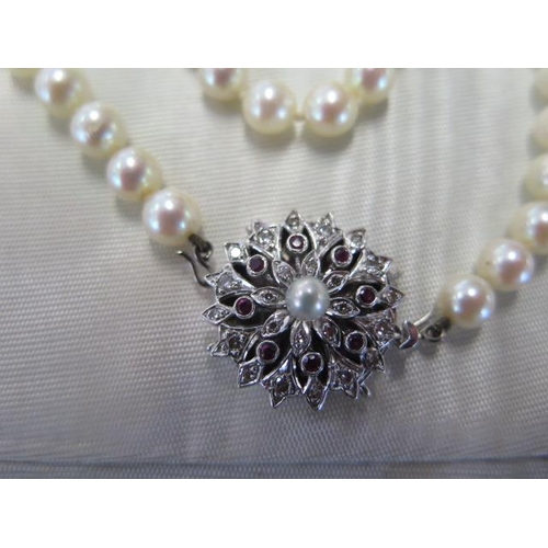 472 - A pearl necklace approx 74cm long with a diamond and ruby clasp - clasp approx 21mm diameter - pearl... 