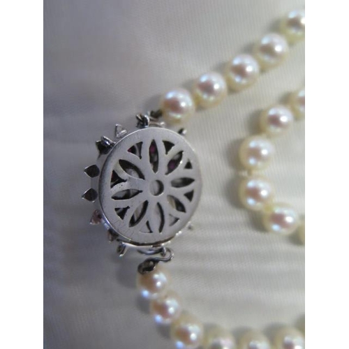 472 - A pearl necklace approx 74cm long with a diamond and ruby clasp - clasp approx 21mm diameter - pearl... 