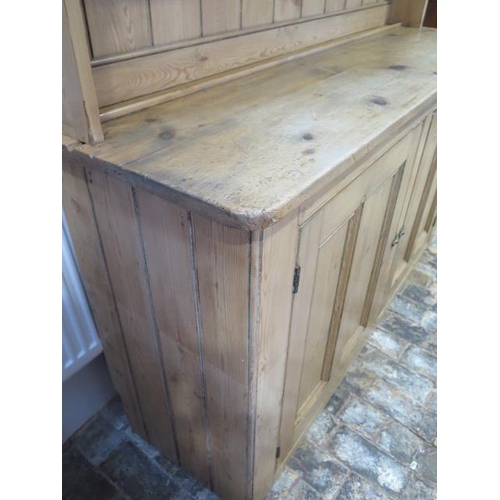 69 - A Victorian stripped pine kitchen dresser with an open rack top above a two door base - Height 211cm... 