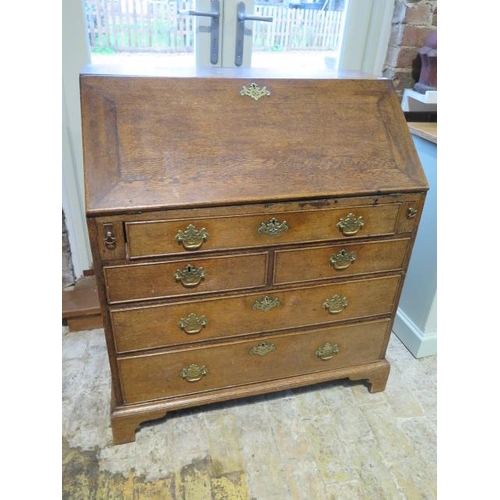 564 - A Georgian oak bureau with a well and fitted interior above two short and three long drawers on brac... 