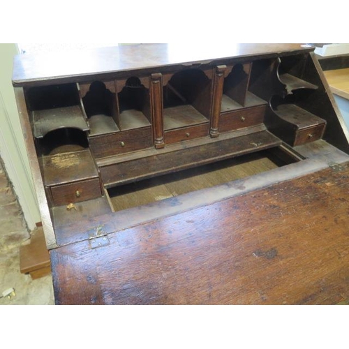 564 - A Georgian oak bureau with a well and fitted interior above two short and three long drawers on brac... 