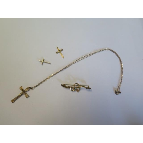 64 - A 9ct yellow gold crucifix on a gilt metal chain, two 9ct crucifixes and a 9ct brooch with steel pin... 