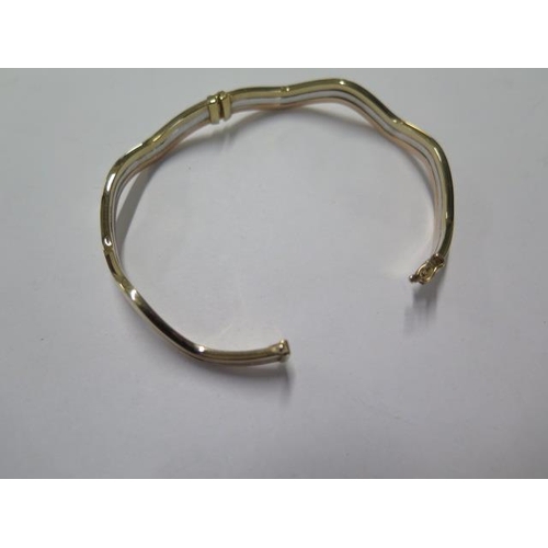 4 - A 9ct tricolour gold wavy bangle approx weight 8 grams - 6cm external diameter - good condition