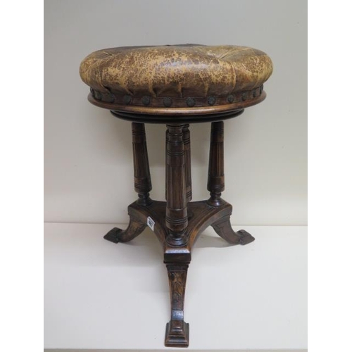 467 - A Victorian walnut revolving piano music stool with a leather button seat