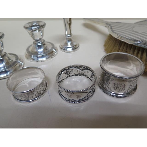 103 - A collection of assorted silver to include a brush and mirror, a pair of dwarf candle sticks - weigh... 