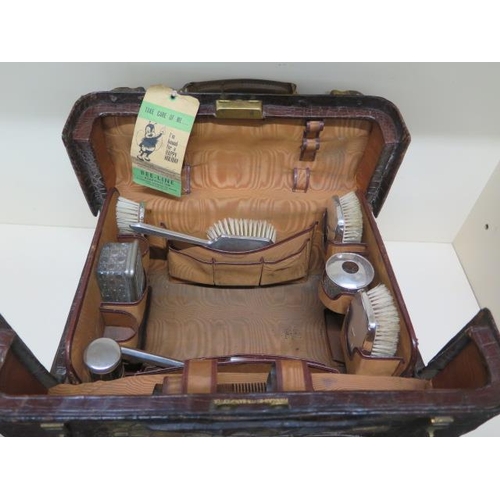 284 - An early 20th century crocodile travel case by Finnigan makers with a fitted interior including seve... 