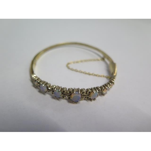 81 - A yellow gold hinged bracelet set with faux opals - 6cm x 5.5cm external - approx weight 11.8 grams ... 