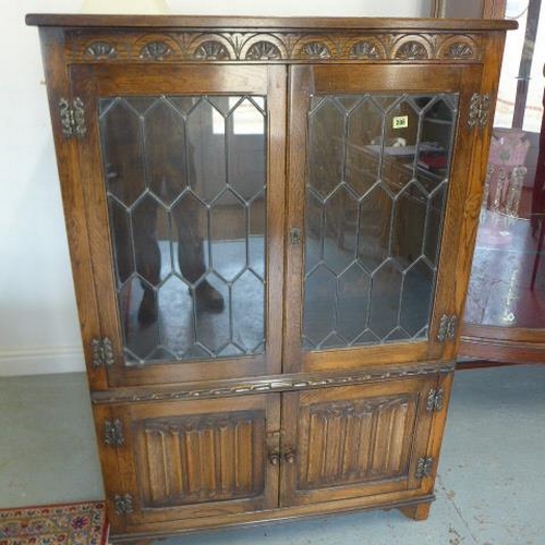 579 - An oak display cabinet/bookcase the top with leaded glazed doors and two linen fold lower doors - He... 