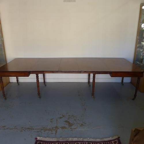 581 - A Georgian mahogany pull out dining table with three leaves raised on eight turned legs with brass c... 