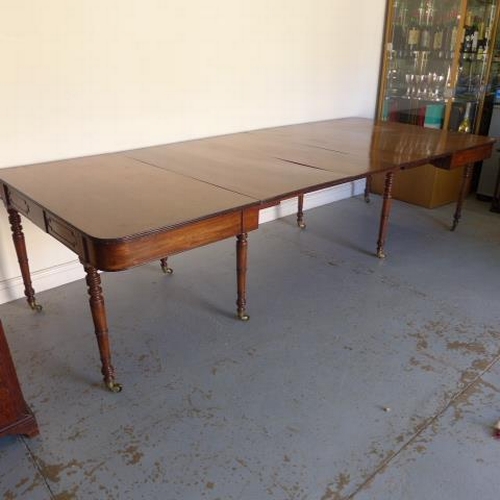 581 - A Georgian mahogany pull out dining table with three leaves raised on eight turned legs with brass c... 