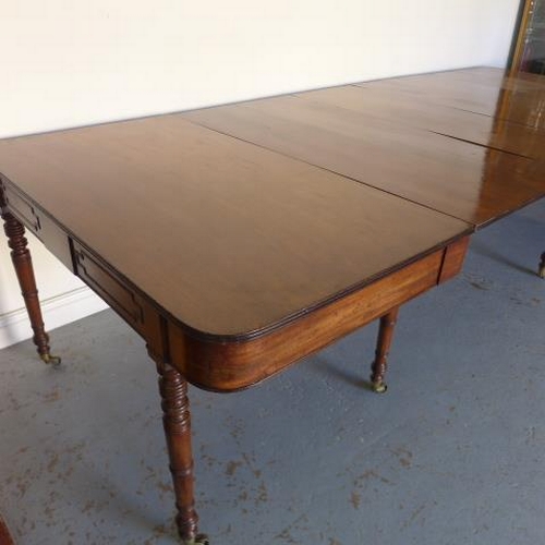 581 - A Georgian mahogany pull out dining table with three leaves raised on eight turned legs with brass c... 