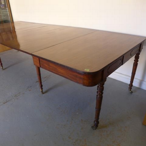 581 - A Georgian mahogany pull out dining table with three leaves raised on eight turned legs with brass c... 