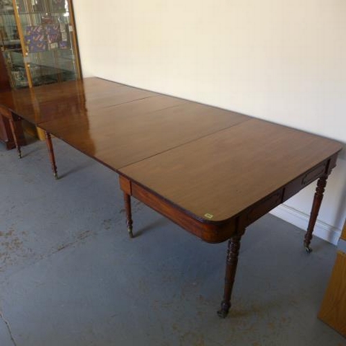 581 - A Georgian mahogany pull out dining table with three leaves raised on eight turned legs with brass c... 