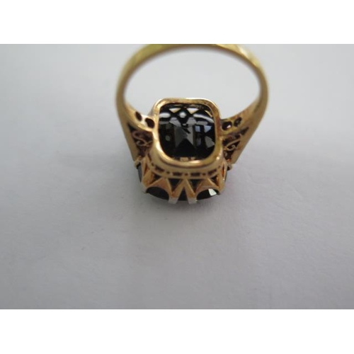 146A - An 18ct yellow gold ring with a large centre stone possibly a sapphire with diamonds to the sides, c... 