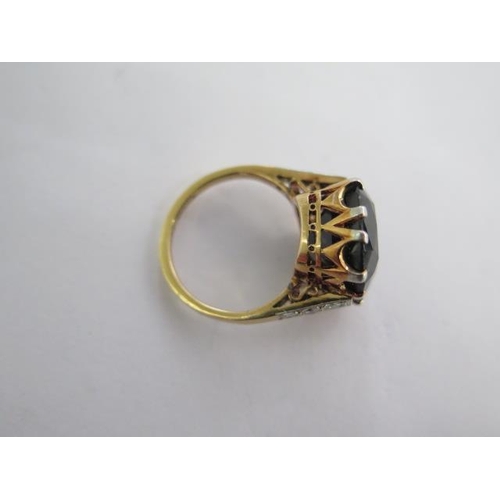 146A - An 18ct yellow gold ring with a large centre stone possibly a sapphire with diamonds to the sides, c... 