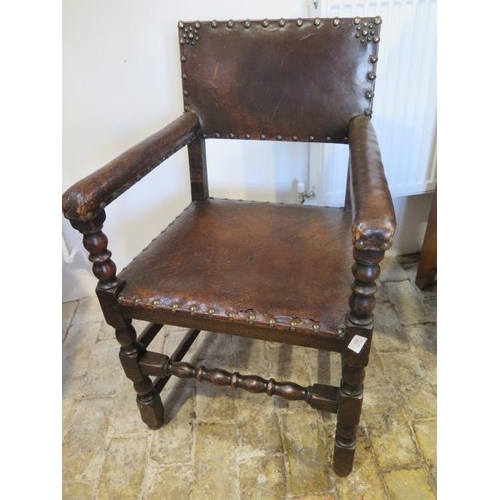 592 - A 17th/18th century oak armchair with a worn leather seat back and arms - sound condition and a nice... 