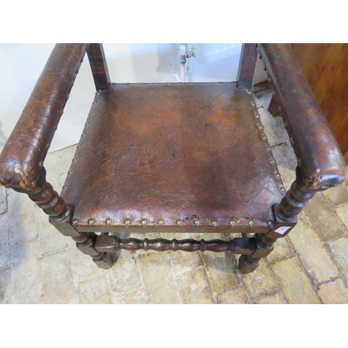 592 - A 17th/18th century oak armchair with a worn leather seat back and arms - sound condition and a nice... 