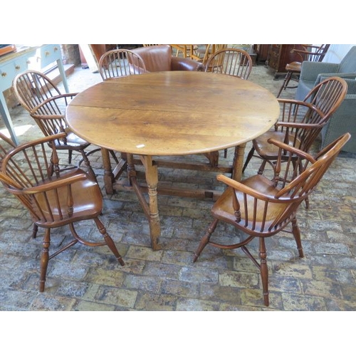 653 - A good quality oak or yewwood oval gateleg dining table with six Windsor armchairs with crinoline st... 