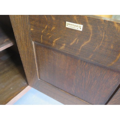 566 - A Liberty Arts & Crafts oak dresser with a glazed single door and two shelves over the base with a s... 