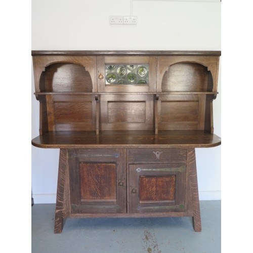 566 - A Liberty Arts & Crafts oak dresser with a glazed single door and two shelves over the base with a s... 