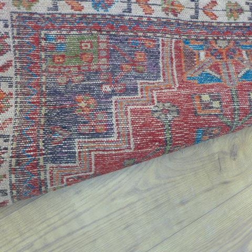 561 - A small hand knotted woollen rug with a red field - 137cm x 90cm - some wear mainly to fringes, gene... 