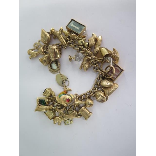A 9ct yellow gold charm bracelet with 35 assorted charms - approx total weight 76 grams