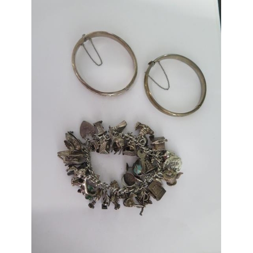 49 - A silver charm bracelet and two silver bangles - total weight approx 143 grams