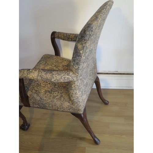 656 - A carved mahogany upholstered open armchair with scroll arms on carved front legs and ball and claw ... 